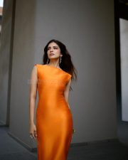 Alluring Actress Malavika Mohanan in a vibrant orange sleeveless fitted midi dress photos 04