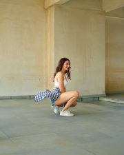 Attractive Pragya Jaiswal in a White Sports Bra with Blue Checkered Plaid Shirt and High Waisted Frayed Denim Shorts Photos 02