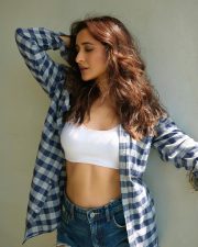 Attractive Pragya Jaiswal in a White Sports Bra with Blue Checkered Plaid Shirt and High Waisted Frayed Denim Shorts Photos 06